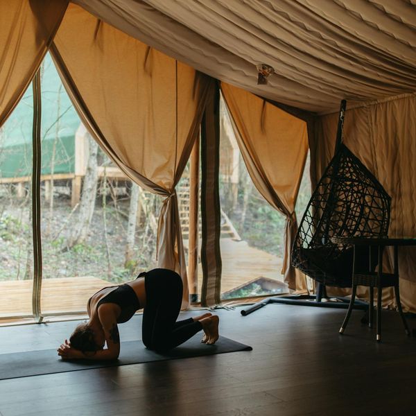 Person stretching peacefully on a yoga mat by a large window.